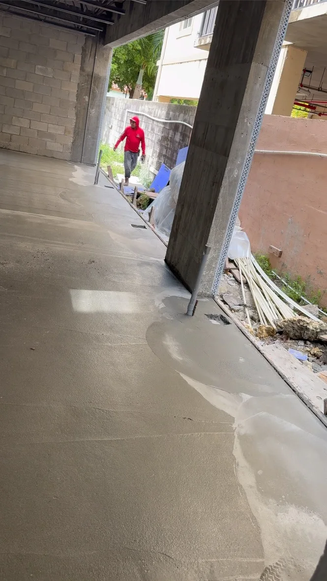 Crew member screeding and finishing freshly placed concrete during the Leslie House build.
